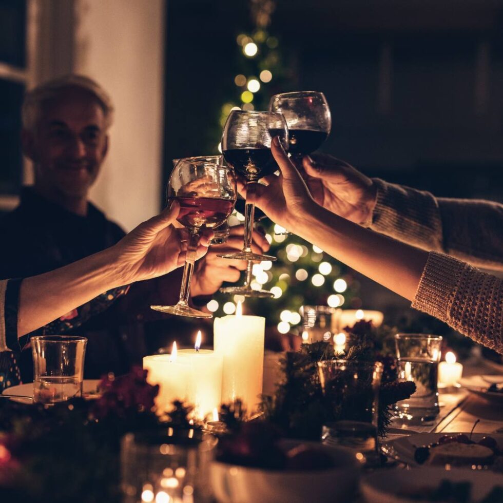 People making a toast with wine with christmas decoration in the back