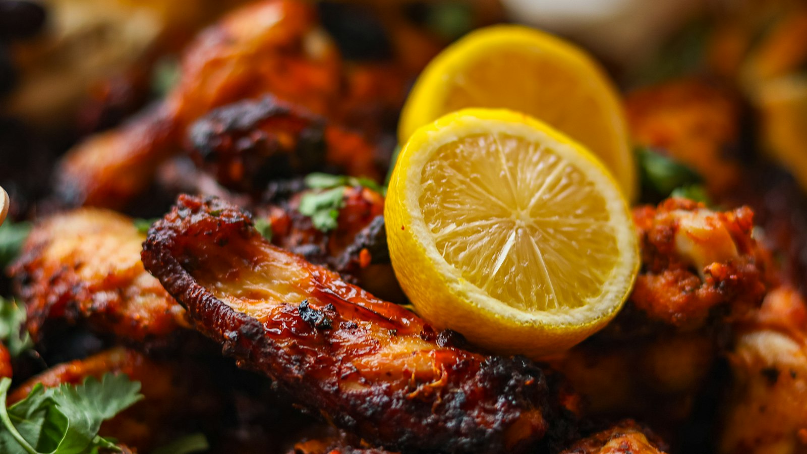 Close-up of glazed chicken wings with a lemon garnish